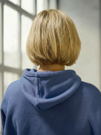 Model wearing Bou Clothing’s Denim Blue luxury Deryn hoodie a in a softly lit modern interior, showcasing a relaxed fit, premium fabric, and minimalist neutral style.