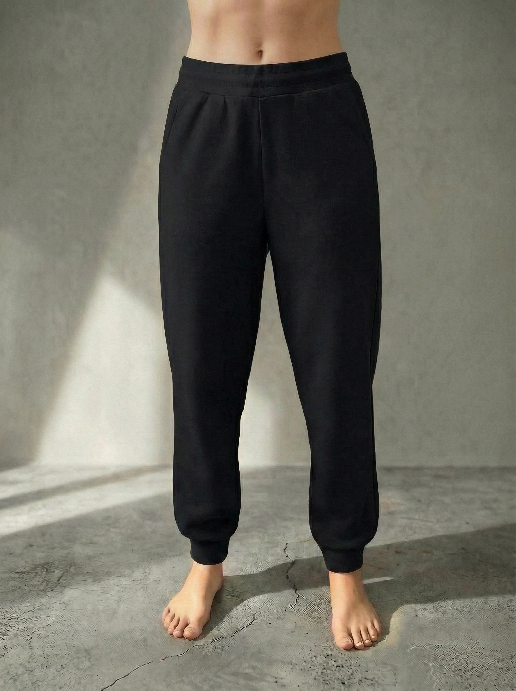 Front iew of the Deryn women’s luxury jogger pants Black colour, by BOU Clothing shown on a model standing barefoot against a stone grey  backdrop.