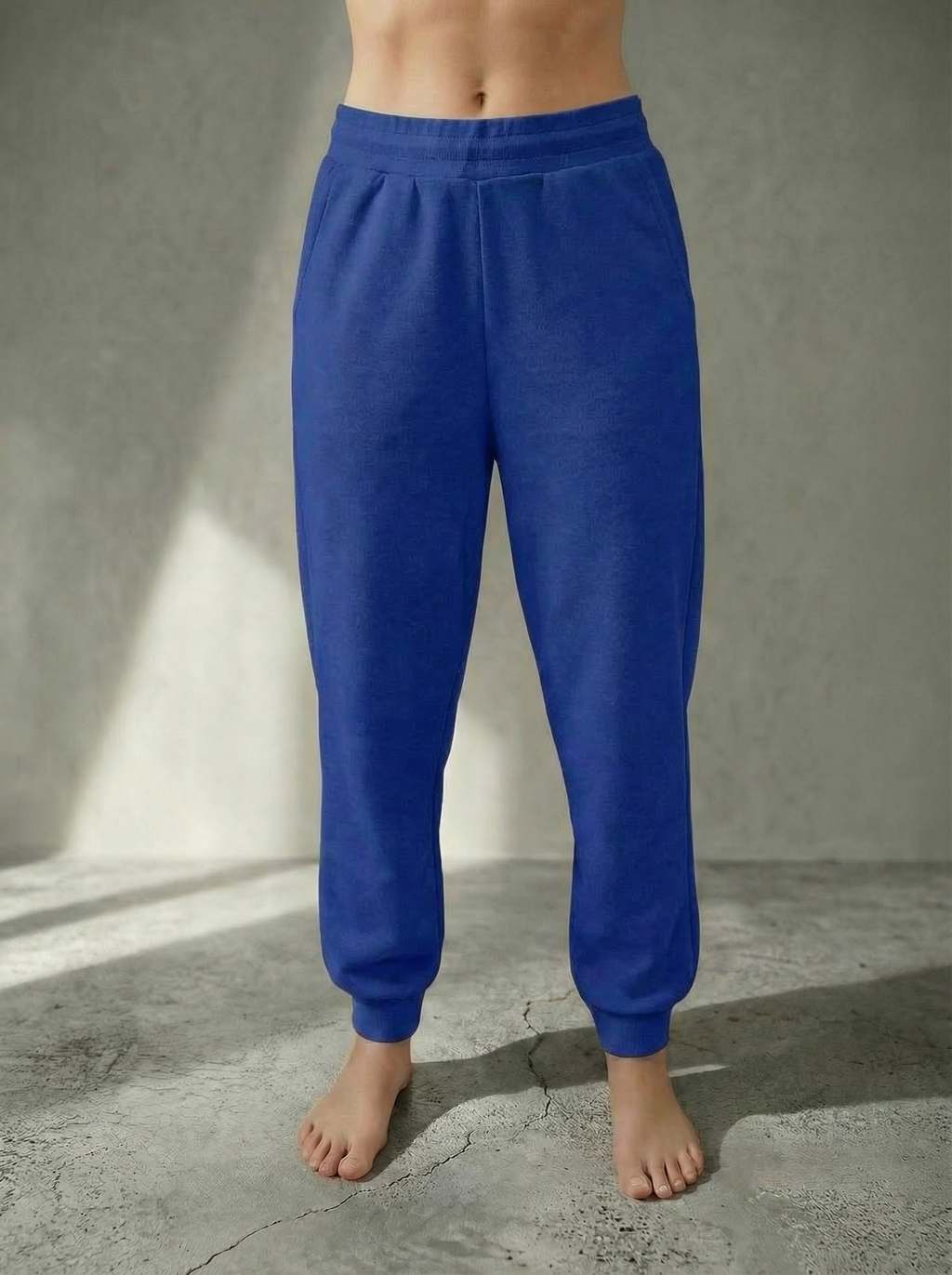 Front view of the Deryn women’s luxury jogger pants Cornflower colour, by BOU Clothing shown on a model standing barefoot against a stone grey  backdrop.