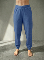 Front view of the Deryn Jogger women’s luxury jogger pants in Denim, by BOU Clothing shown on a model standing barefoot against a stone grey  backdrop.