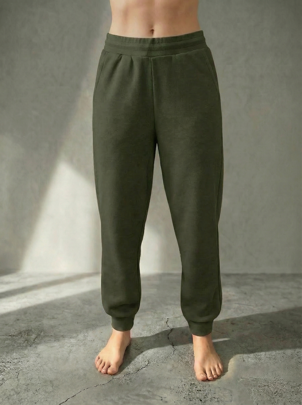 Front view of the Deryn Jogger women’s luxury jogger pants in Forrest colour by Bou Clothing, shown on a model standing barefoot against a stone grey backdrop.